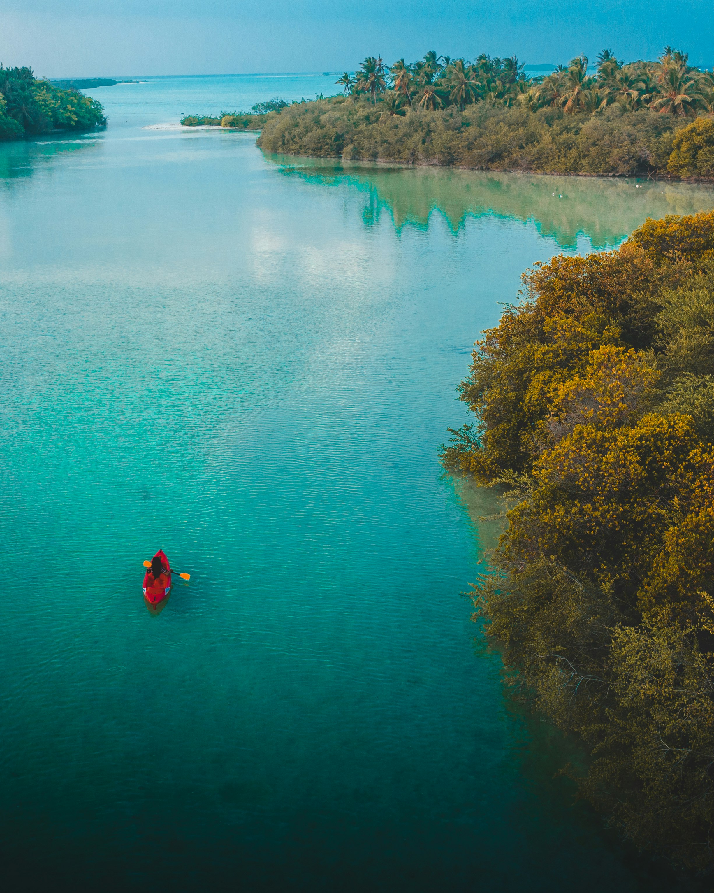 person in red jacket and black pants on red kayak on blue lake during daytime